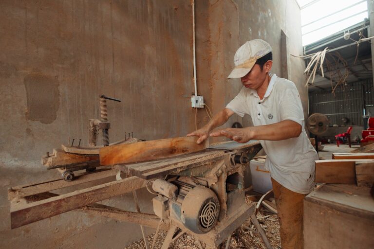 Menuisier qui coupe du bois avec précision dans son atelier, image illustrant un artisan qui veut passer devant ses concurrents sur Google